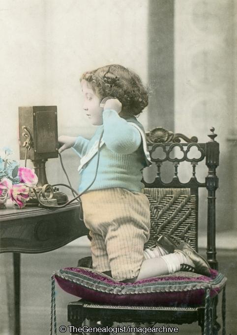 boy on phone kneeling (boy, C1910, chair, cushion, flowers, kneeling, Telephone)