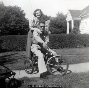 Couple on kids bike (American, Couple , Home, Sunglasses, Tricycle, U.S.A.)
