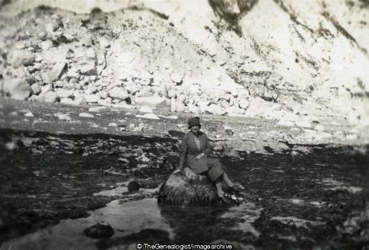 Lady sitting on rocks on seashore (Cliff, Seaside, Woman)