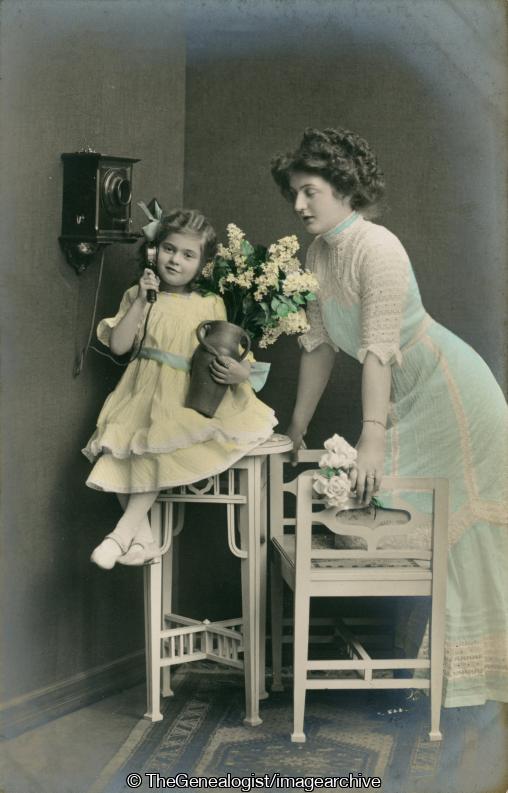 Mother and daughter sitting on table on phone C1900 (C1900, daughter, dress, flowers, Mother, sitting, table, Telephone, vase)