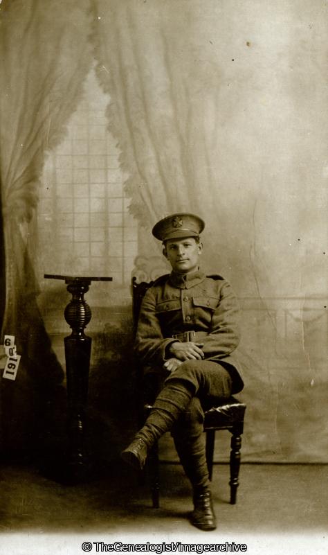 Soldier posing on chair in front of curtains (C1915, London, Soldiers)